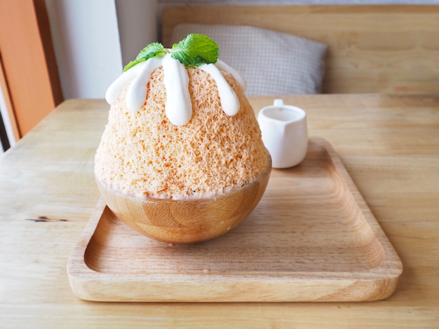 Milchtee Bingsu (koreanischer Nachtisch) auf hölzerner Platte.