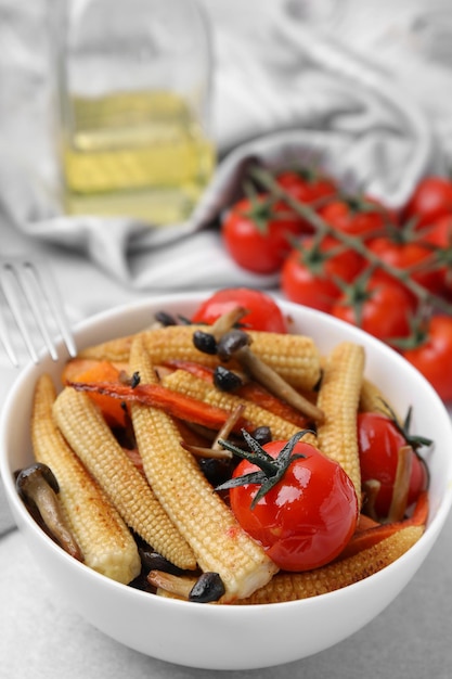 Milho assado saboroso com tomates e cogumelos na mesa cinza clara fechada