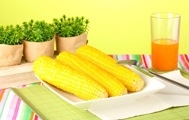 Foto milho cozido e suco em um fundo verde