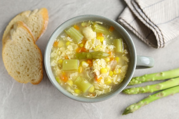 Milho e aspargos com sopa de ovo em tigela branca e pão crocante