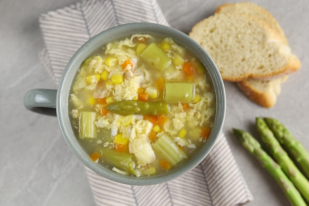 Milho e aspargos com sopa de ovo em tigela branca e pão crocante