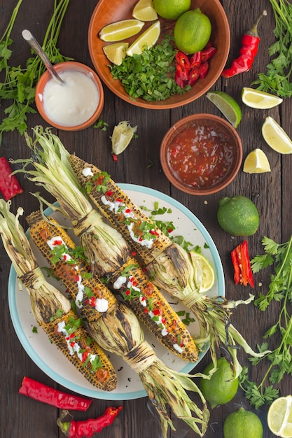 Milho grelhado mexicano com molho de pimenta picante na mesa de jantar, vista de cima