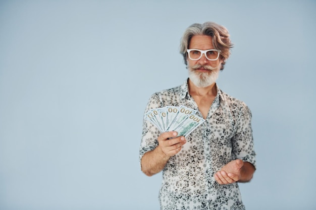 Foto milionário com dinheiro nas mãos homem moderno elegante sênior com cabelos grisalhos e barba dentro de casa