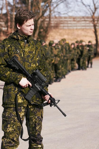 Militär und soldat der armee mit einer waffe auf einem schlachtfeld, bereit für einen kriegskampf oder eine mission mit mut und loyalität gegenüber einem landhelden im freien und einem professionellen mann im dienst, der ein gewehr in ausrüstung hält