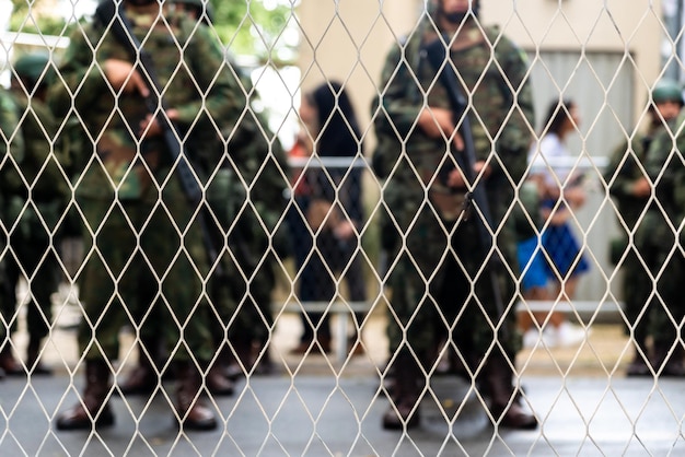 Foto militärangestellte der armee stehen mit waffen in den händen hinter einem gardengleis
