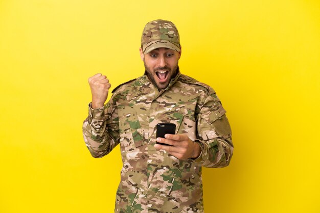 Militärmann isoliert auf gelbem Hintergrund überrascht und sendet eine Nachricht