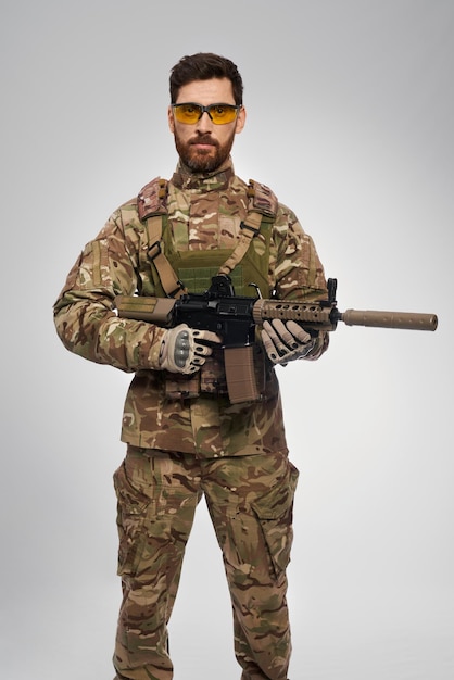 Foto militar armado posando com arma de assalto na vista frontal do estúdio de um soldado de infantaria de meia idade em