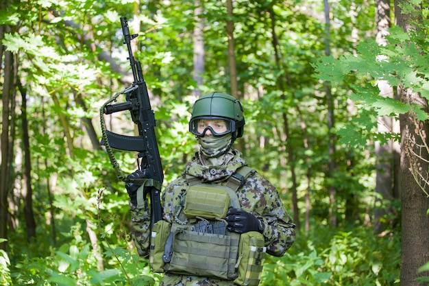 Un militar en el bosque con una ametralladora en tiempos de paz. Preparar a los militares para las hostilidades.
