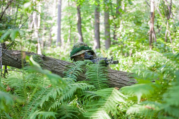 Un militar en el bosque se encuentra en una emboscada. Ametralladora y ropa de soldado