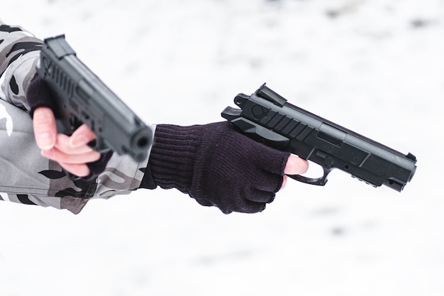 Militar camuflado e luvas apontando de duas pistolas.