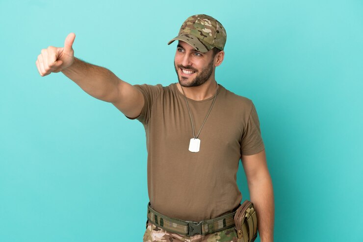 Foto militar com etiqueta de identificação isolada em fundo azul fazendo um gesto de polegar para cima