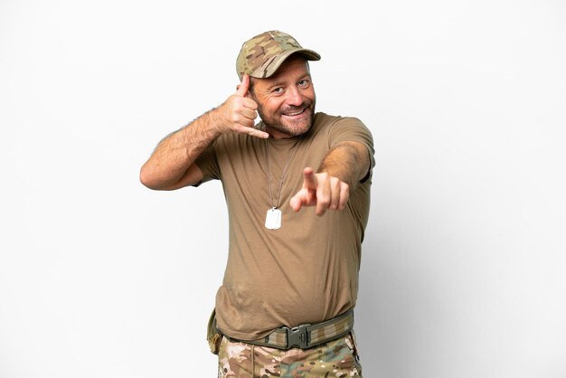 Militar de meia-idade com dog tag isolado no fundo branco, fazendo gesto de telefone e apontando para a frente