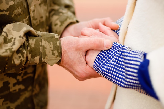 Un militar ucraniano sostiene los dedos de su esposa en sus manos Boda durante la guerra El amor ganará Poder glorioso