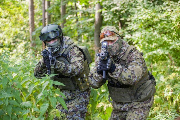 Militares na floresta com uma metralhadora. Soldados estão prontos para a ação
