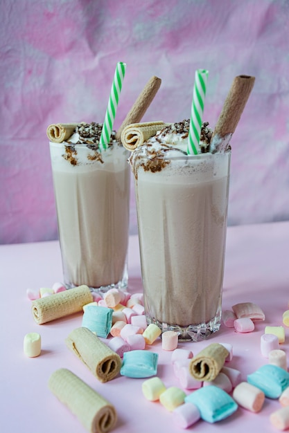 Milk-shake de chocolate com sorvete e chantilly, marshmallows, cookies, waffles, servidos em um copo de vidro.