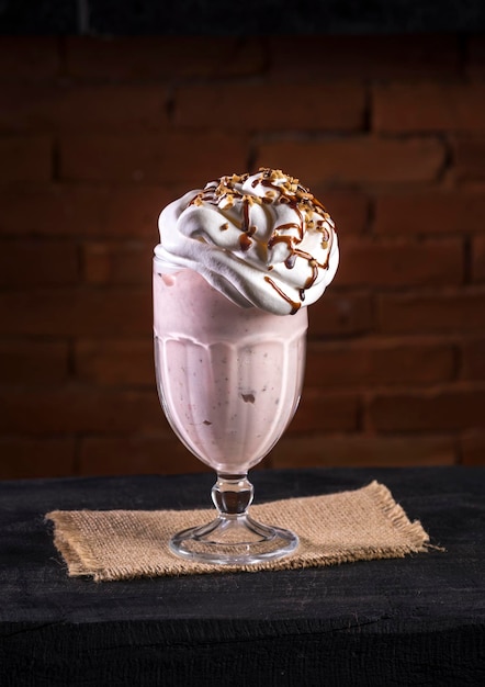 Milk-shake de morango com chantilly em madeira preta, com tijolos no fundo