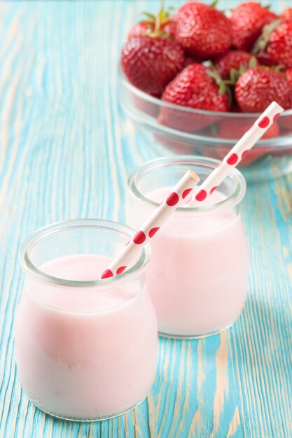 Milk-shake de morango na jarra de vidro com canudo na mesa de madeira azul