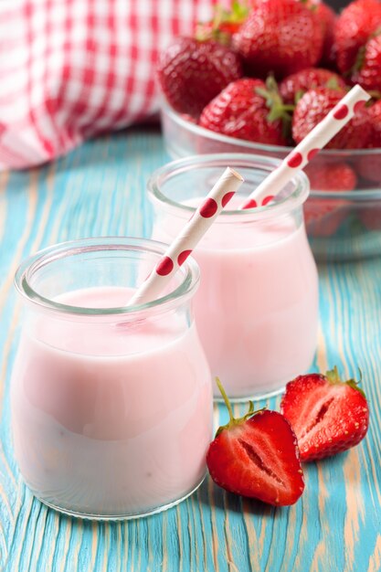 Milk-shake de morango na jarra de vidro com canudo na mesa de madeira azul