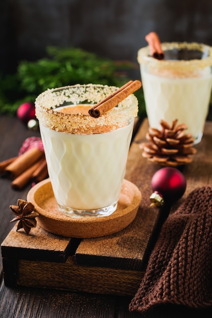 Milkshake de bebida de Natal tradicional de gemada com canela em fundo escuro antigo.