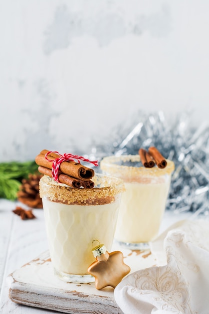 Milkshake de bebida tradicional de Natal de gemada com canela na mesa velha clara.