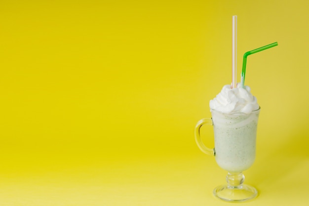 Milkshake de hortelã-pimenta verde frio em um fundo amarelo.