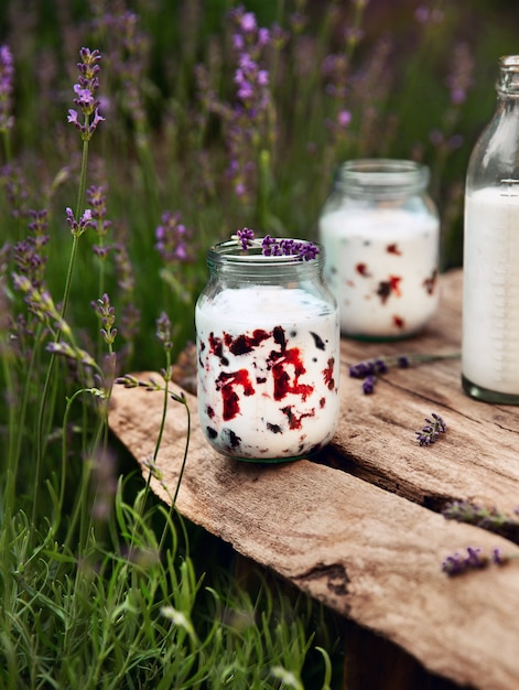 Milkshake de mirtilo em frasco de vidro na velha placa de madeira no jardim perto da lavanda florescendo