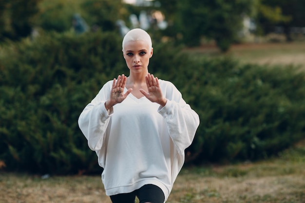 Millenial junge Frau blonde kurze Haare im Freien beim Qigong