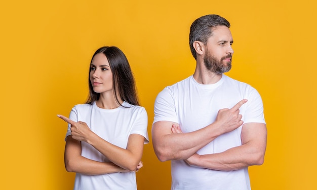 Millennial Mann und Frau machen Angebot Angebot von Millennial Paar Freund und Freundin zeigen Finger Paar von Mann und Frau isoliert auf Gelb Familie Paar zeigen Finger Zeigen, um anzubieten