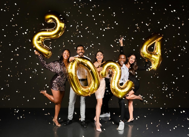 Millennials multiétnicos felices celebrando el año nuevo juntos fondo negro