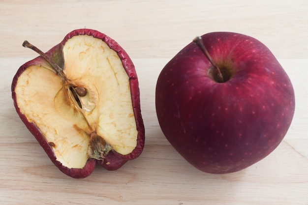 Foto mimado uma má maçã vermelha em fundo de madeira maçãs saudáveis ​​e podres