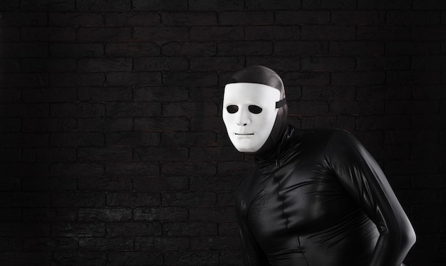 Foto mimo divertido en una máscara blanca sobre un fondo negro