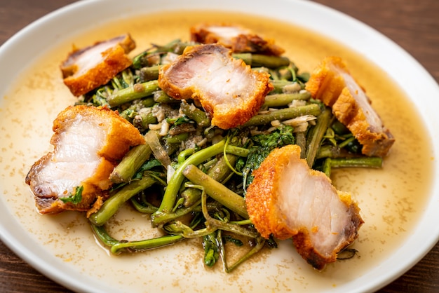 Mimosa de agua salteada con crujiente panceta de cerdo en un plato