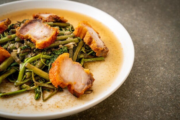 Mimosa de agua salteada con panceta de cerdo crujiente en un plato