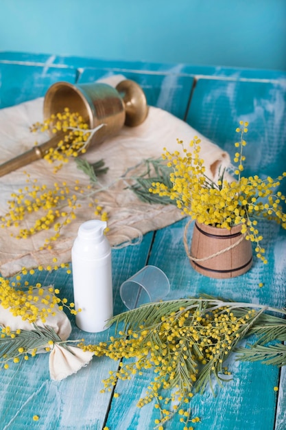 Mimosa-Gesichtscremespender auf einer cyanfarbenen Holzoberfläche. Nahaufnahme