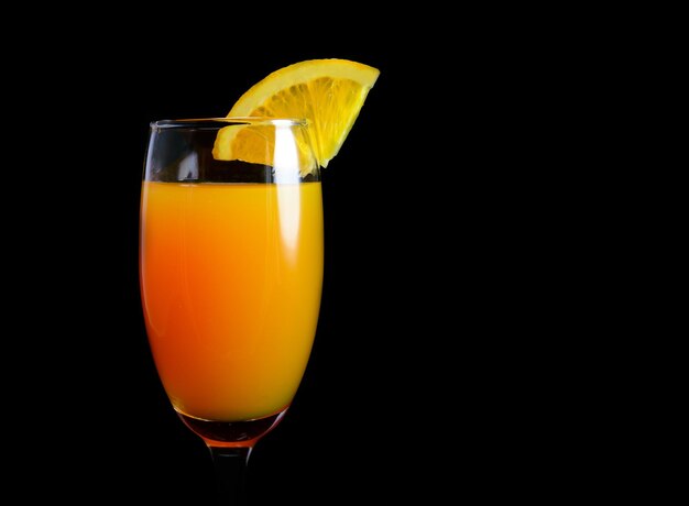 Mimosencocktail mit einer Orangenscheibe auf schwarzem Hintergrund Nahaufnahme