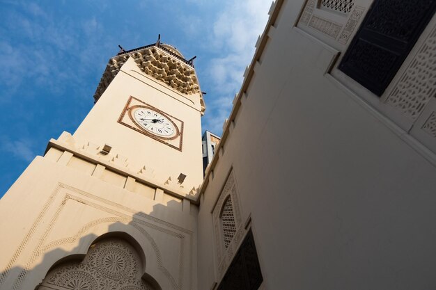 Foto el minarete cuadrado de la mezquita abdulla ali yateem con cuatro relojes y decorado con muqarnas en manama, bahréin