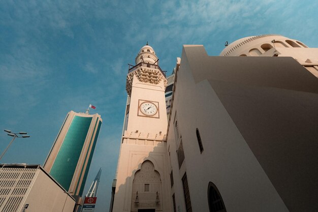 Minarete quadrado da Mesquita Abdulla Ali Yateem com quatro relógios e decorar com muqarnas em Manama, Bahrein