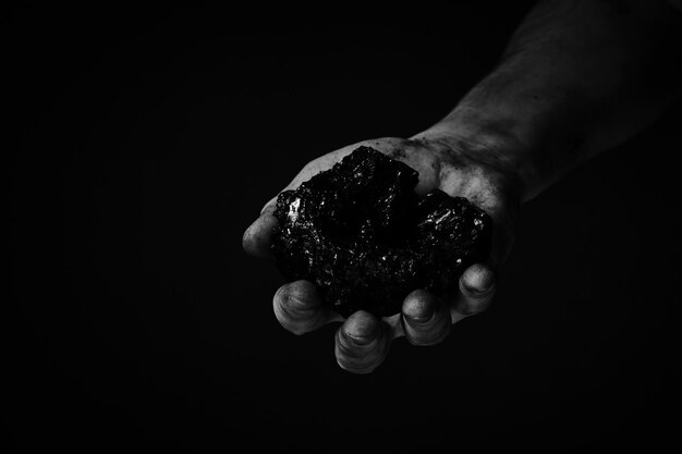 Mineiro de mãos sujas segurando carvão em foto preto e brancoMineração de carvão pesada