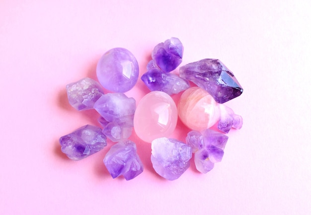 Mineralien von Edelsteinen auf rosa Hintergrund. Wunderschöne violette Amethystkristalle und Rosenquarzmineralien