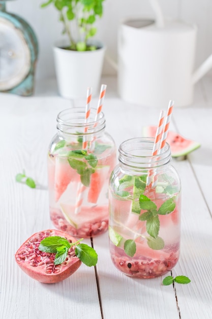 Mineralwasser im Glas mit Wassermelonengranatapfel und Minzblättern