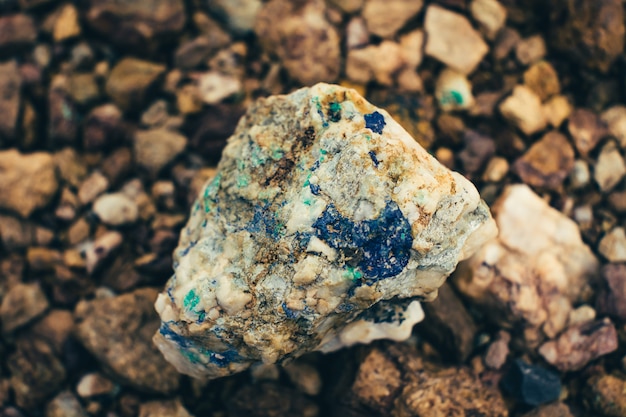 Minério cru em close-up à terra. Pedra áspera multicolor na luz solar. Geológico vívido Textured com a pilha de pedras rudes. Textura natural com espaço de cópia. Mineral incrível. Pedaço de pedra.