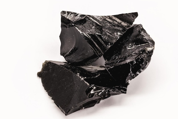 Minério preto e cristalino de obsidiana negra em fundo branco isolado pedra de cor preta terapêutica usada em meditação