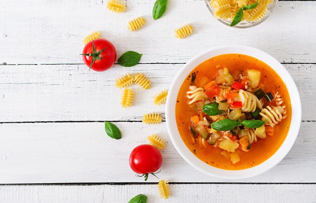 Minestrone, sopa de legumes italianos com macarrão na mesa de madeira