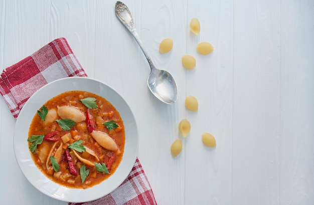 Minestrone Suppe mit Nudeln und Kräutern. Italienische Küche. Weißer hölzerner Hintergrund