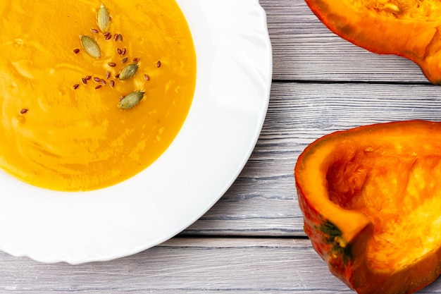 Foto mingau de abóbora em um prato branco sobre uma sopa cremosa de fundo de madeira clara para vegetarianos