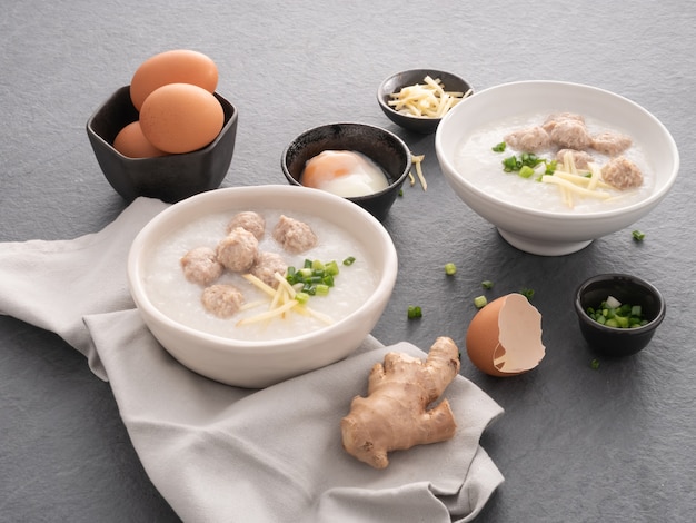 Foto mingau de arroz com carne de porco picada em tigela branca. tigela de mingau de arroz com ovo cozido macio. café da manhã asiático