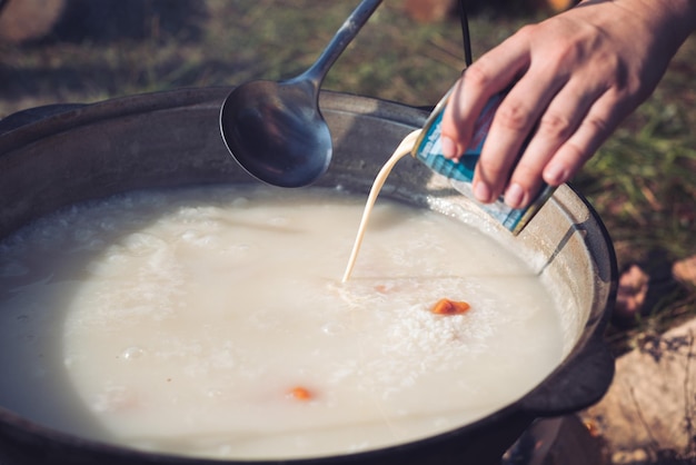 Mingau de arroz doce com damascos secos em um grande caldeirão sobre uma fogueira no acampamento