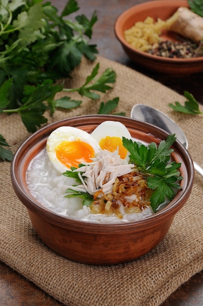 Mingau de arroz, gengibre mingau com ovo, galinha, chalotas crocantes e salsa