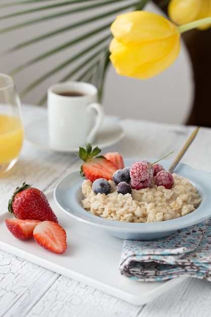 Mingau de aveia de café da manhã com frutas bagas e xícara de café. Aveia com morangos e bagas. Café da manhã saudável Conceito inglês caseiro delicioso do café da manhã para o fundo.