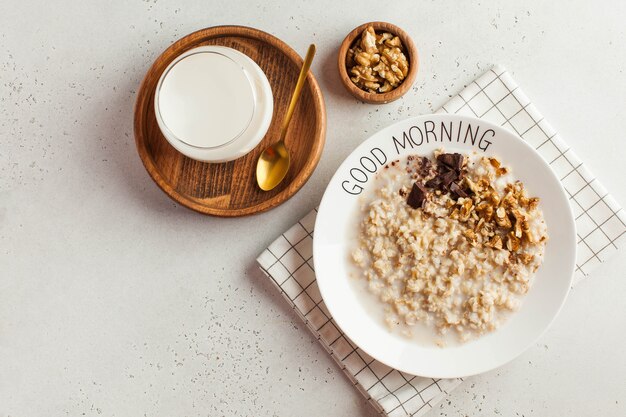 Mingau de aveia em um prato que diz bom dia e um copo de leite. Comida saudável. Café da manhã.